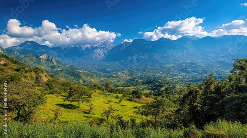 Panoramic view of majestic mountain peaks surrounded by lush greenery and vibrant clouds under a bright blue sky in a picturesque landscape.