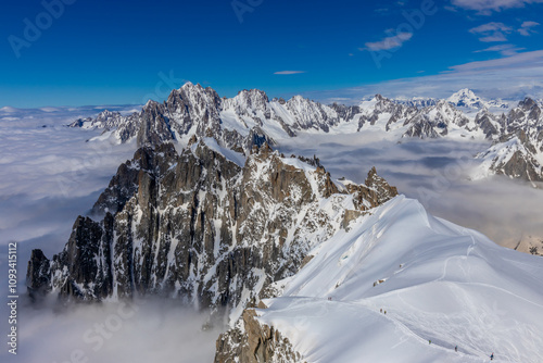 Snow mountains view in the Alps from Aiguille du Midi summit. Rocky mountain peaks scene covered with snow and ice of huge alpine glacier on the massive du Mont Blanc range in Chamonix