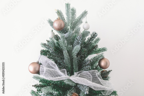 Decorated Christmas pine tree decorated with white gold ornaments and garlands isolated on white wall cerebrate for happy holiday and new year photo