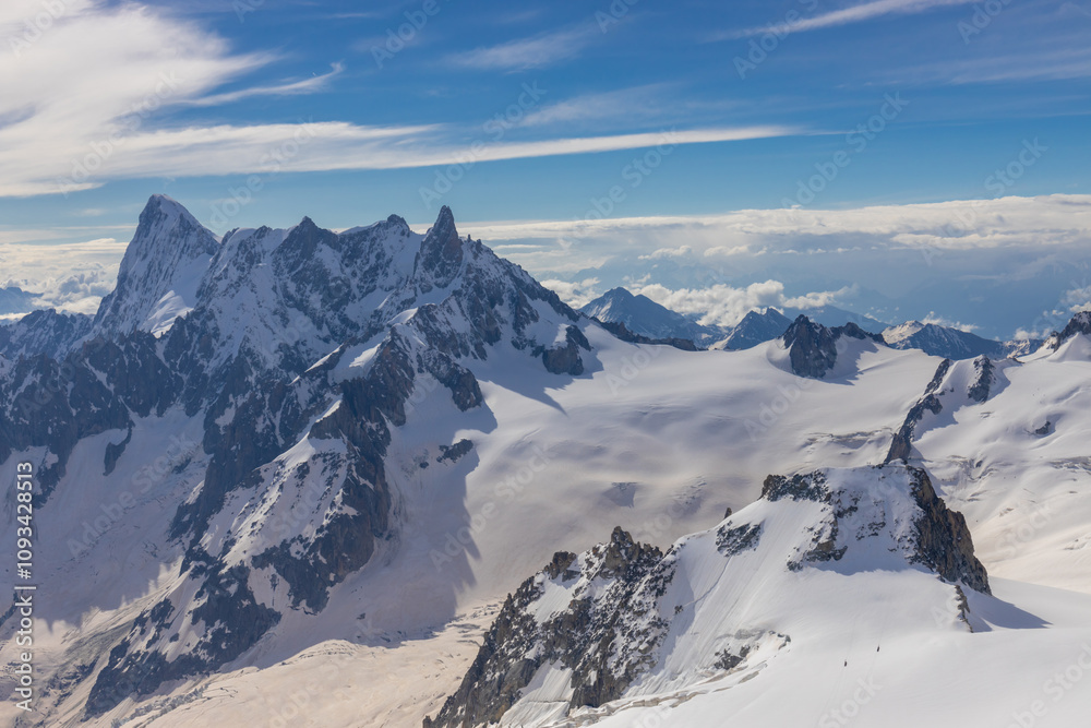 Obraz premium Snow mountains view in the Alps from Aiguille du Midi summit. Rocky mountain peaks scene covered with snow and ice of huge alpine glacier on the massive du Mont Blanc range in Chamonix