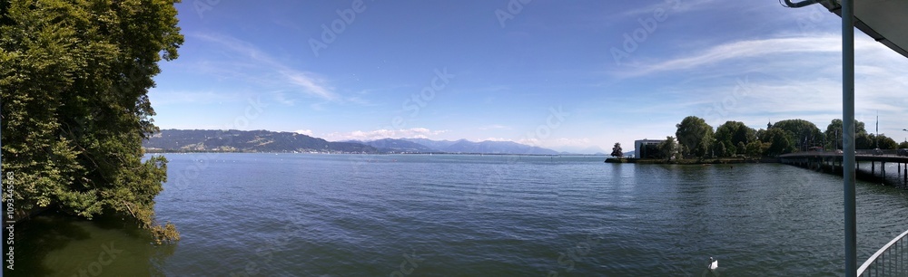 Panoramic view of Lake Constance with blue sky and mountains. Panoramic view of Lake Constance with blue sky and mountains.