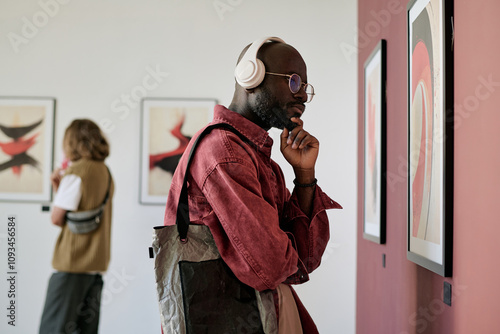 Slika na platnu Man standing in art gallery viewing modern abstract artworks hanging on walls, w