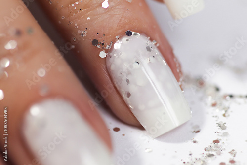 Milky white manicure with glitter on a narrowed nail shape.