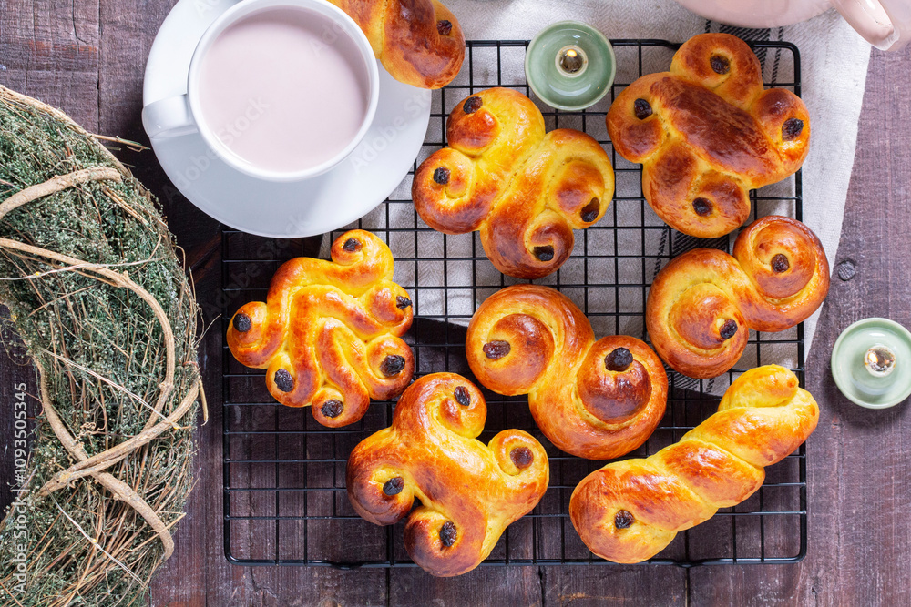 Traditional saffron Swedish buns lussekatt in different shapes, served with cocoa on a wooden table. Buns for St. Lucia's Day.