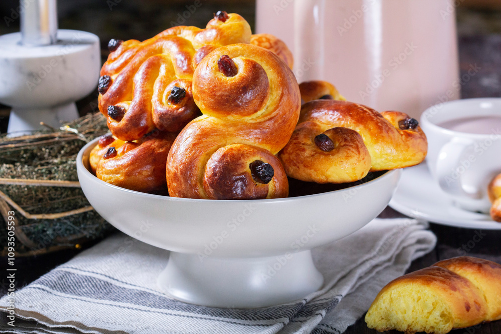 Traditional saffron Swedish buns lussekatt in different shapes, served with cocoa on a wooden table. Buns for St. Lucia's Day.