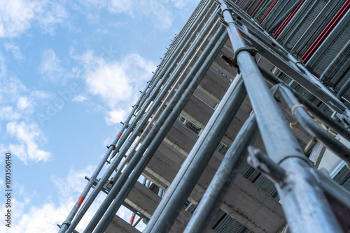 High scaffold looked at from below view against a beautiful blue sky with white clouds.