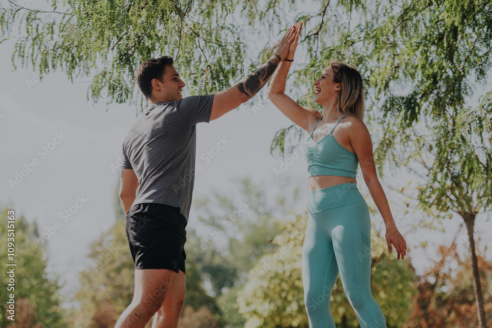Two friends share a high five while exercising outdoors in the park on a sunny day. The vibrant scene captures the essence of fitness, friendship, and an active lifestyle. Two friends share a high five while exercising outdoors in the park on a sunny day. The vibrant scene captures the essence of fitness, friendship, and an active lifestyle.