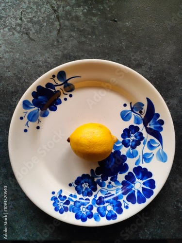 yellow lemon on a white plate decorated with blue flowers