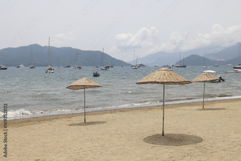 Beach umbrellas against the backdrop of yachts moored at anchor, Marmaris Bay, Turkey, May 2023, 2 Beach umbrellas against the backdrop of yachts moored at anchor, Marmaris Bay, Turkey, May 2023, 2