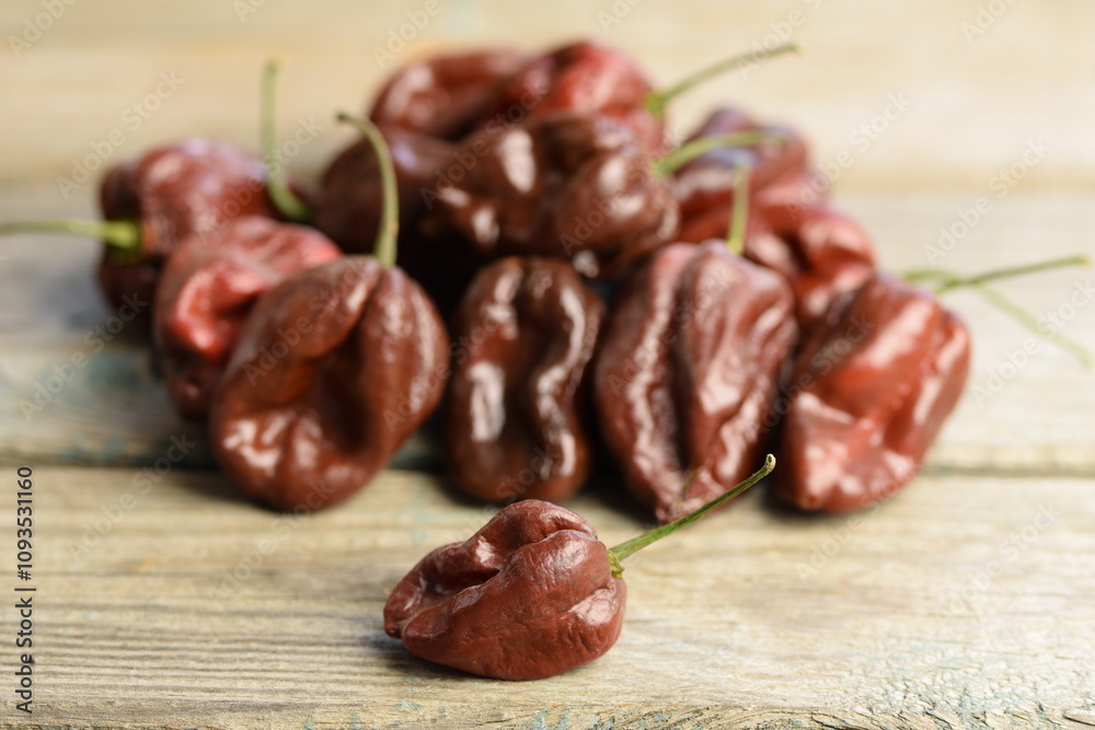 Brown Habanero peppers on wooden background, Habanero Chocolate, selective focus, bokeh, red habanero background, pepper background, space for text, copy space. Brown Habanero peppers on wooden background, Habanero Chocolate, selective focus, bokeh, red habanero background, pepper background, space for text, copy space.