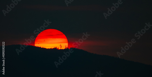 A very smoky sunrise over a mountain with satellite towers