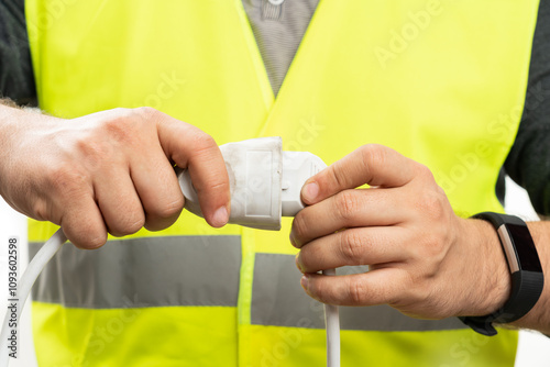 Close-up of electrician plugging in socket on extension cord
