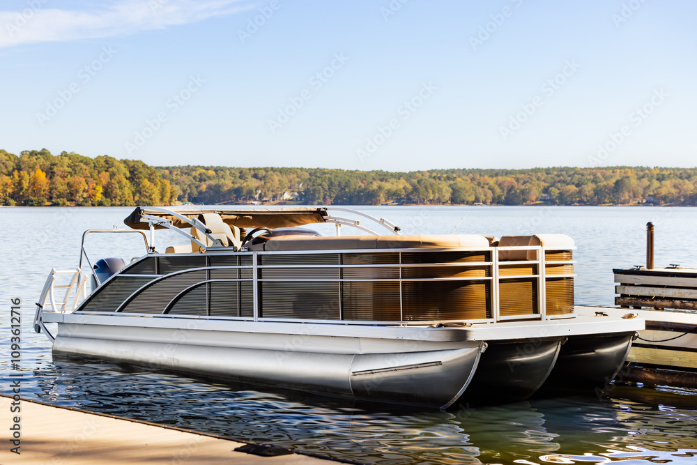 Naklejka premium Pontoon boat at private marina dock on freshwater lake.