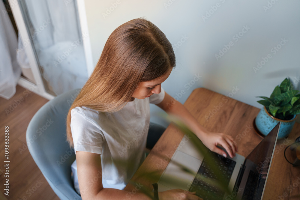 A teenage girl, a student or a schoolgirl, is sitting at a table with a laptop. Kazan, Russia - 13 Aug 2024 A teenage girl, a student or a schoolgirl, is sitting at a table with a laptop. Kazan, Russia - 13 Aug 2024