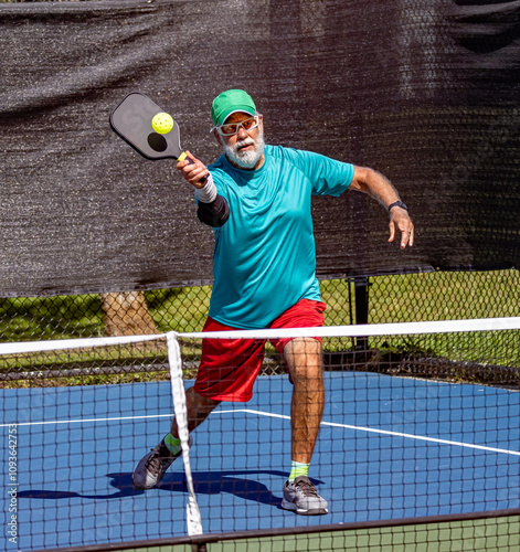 Pickleball player leans in to strike a sharp volley.