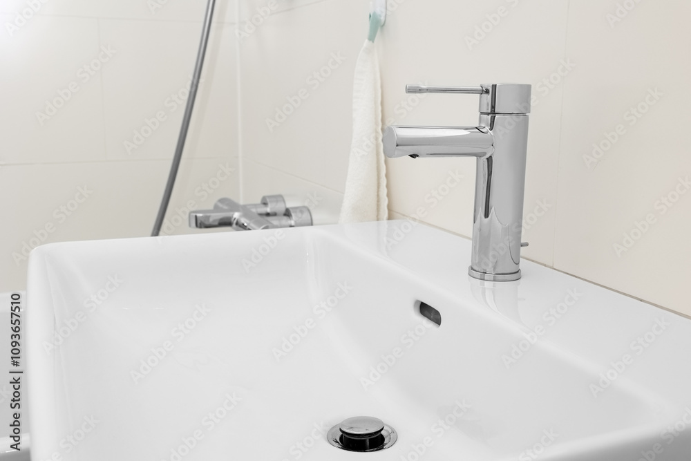 White sink with silver tap in light bathroom, closeup White sink with silver tap in light bathroom, closeup