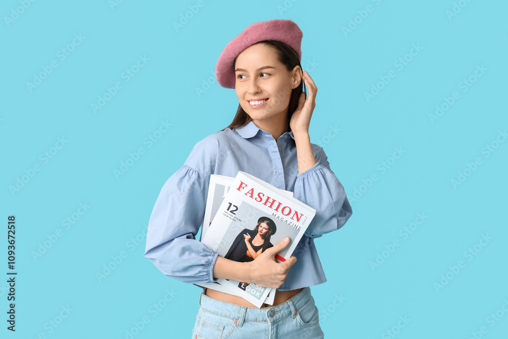 Beautiful young woman in stylish pink beret hat with magazine on blue background Beautiful young woman in stylish pink beret hat with magazine on blue background