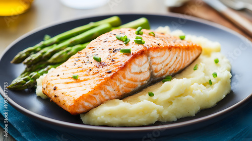 A gourmet dish of seared salmon on a bed of creamy mashed potatoes with vibrant green asparagus.