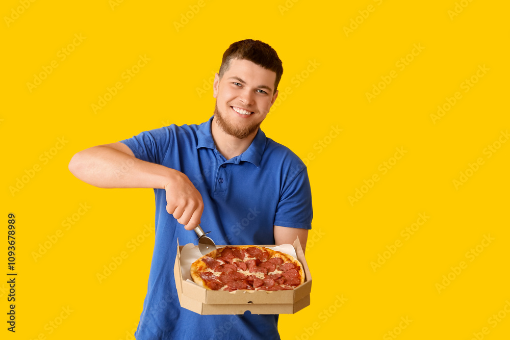 Young man cutting tasty pepperoni pizza on yellow background Young man cutting tasty pepperoni pizza on yellow background