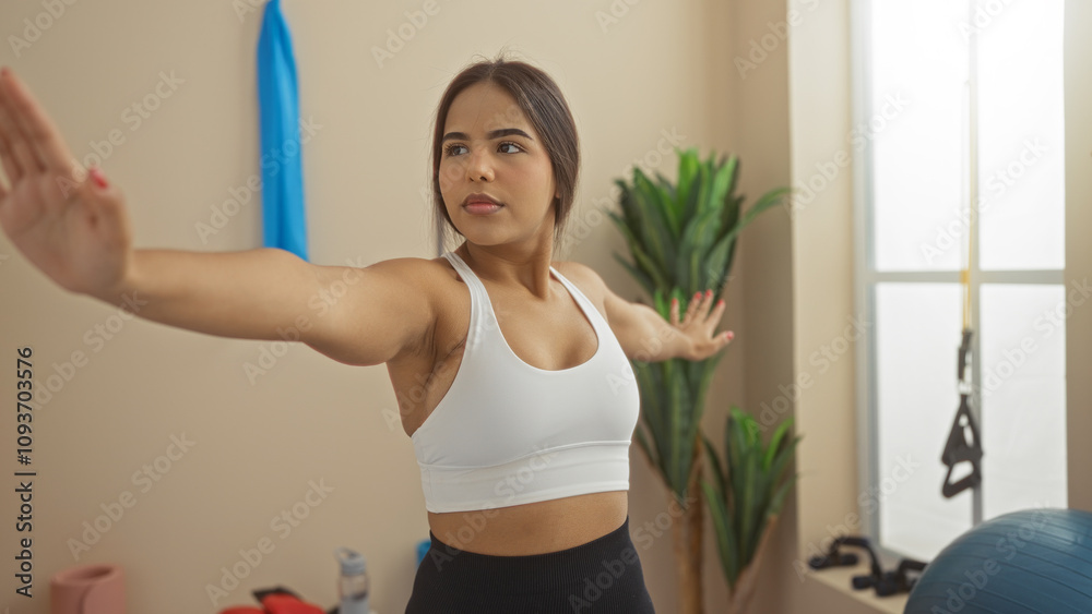 Woman exercising indoors in a bright gym wearing a white top with fitness equipment in view, showcasing a confident and focused workout posture. Woman exercising indoors in a bright gym wearing a white top with fitness equipment in view, showcasing a confident and focused workout posture.