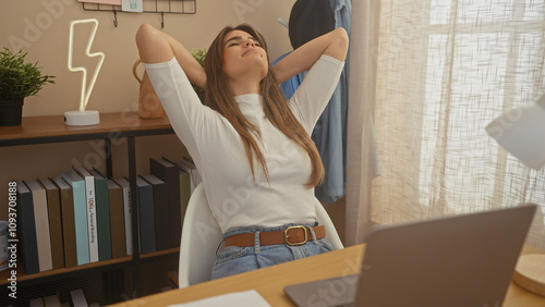 A relaxed young woman stretching with joy in a modern home office setup.