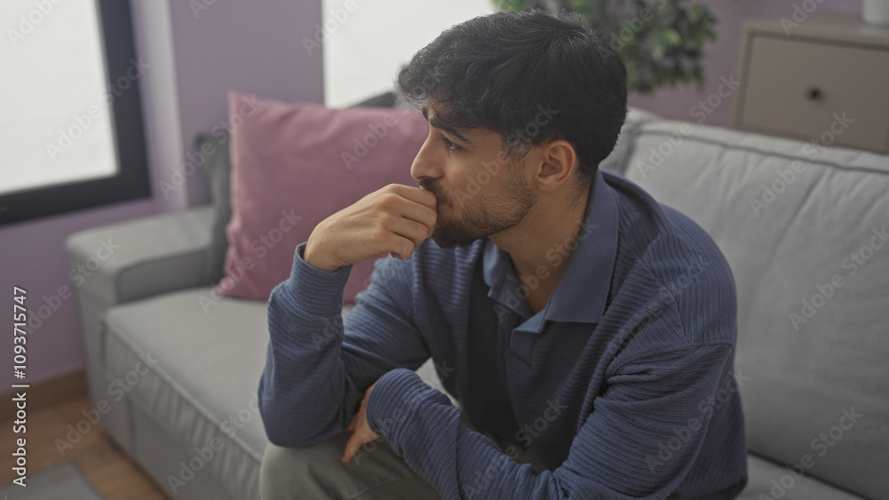 Thoughtful arabian man with beard sitting in a modern living room indoor Thoughtful arabian man with beard sitting in a modern living room indoor