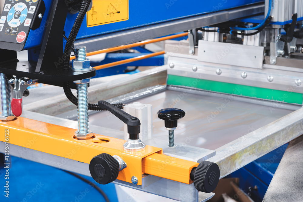 A machine with a green button on it. The machine is orange. The machine is on a blue surface A machine with a green button on it. The machine is orange. The machine is on a blue surface