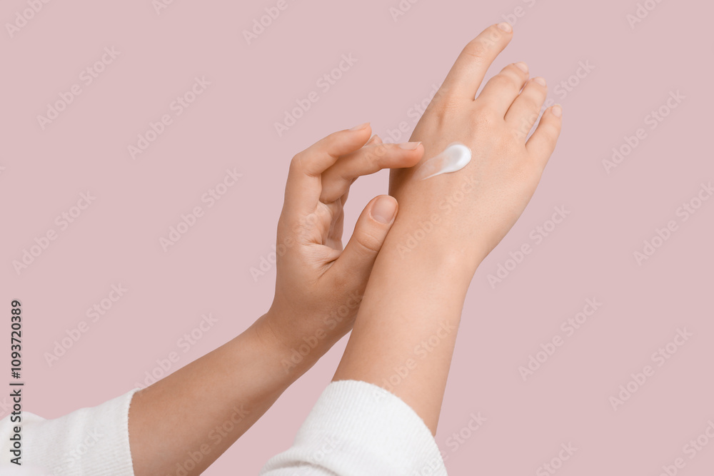 Young woman applying cosmetic cream on her hand against lilac background Young woman applying cosmetic cream on her hand against lilac background