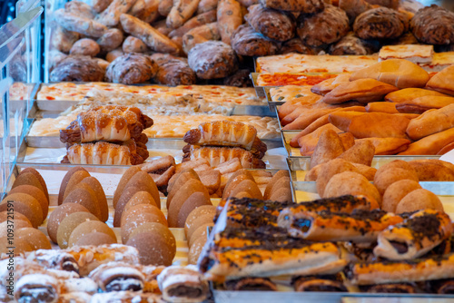 Sicilian bakery, sweet pastry and street food arancini, deep fried rice croquettes with different fillings on market