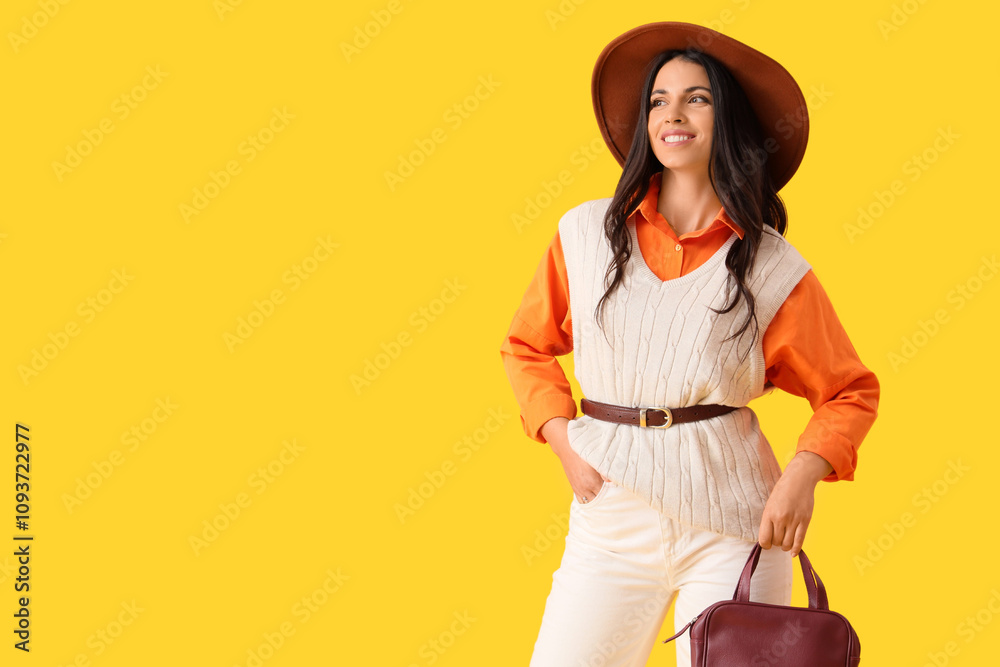 Beautiful young happy woman in autumn outfit with stylish bag on yellow background Beautiful young happy woman in autumn outfit with stylish bag on yellow background