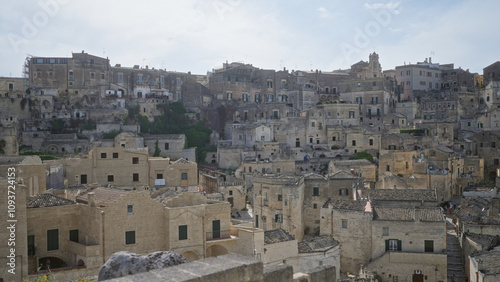 Panoramic view of historic buildings in matera, basilicata, italy, capturing the ancient architecture and stone houses stacked on the hillside under a clear sky.