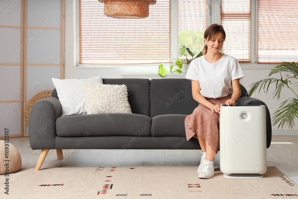 Young woman with air humidifier sitting on sofa at home Young woman with air humidifier sitting on sofa at home