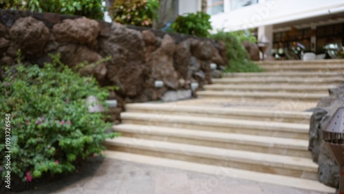 Defocused tropical resort stairway with lush greenery and stone walls in the blurred background