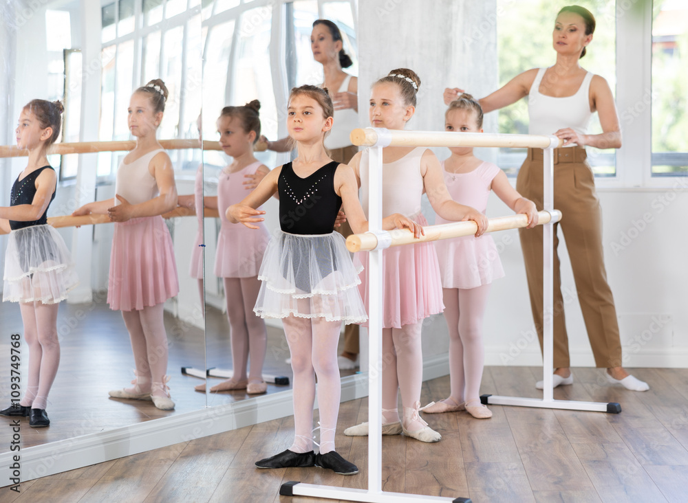 Female teacher conduct training, performs correction of pose in first position students. Girls engaged in ballet studio, perform repetitions of elements and tasks Female teacher conduct training, performs correction of pose in first position students. Girls engaged in ballet studio, perform repetitions of elements and tasks