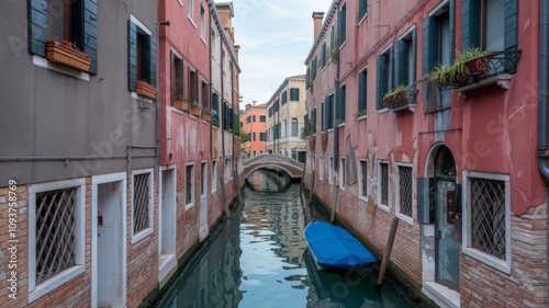 Channels in Italy. There are colorful buildings on both sides of the narrow canal. An arched bridge crossing the canal and a blue-coated boat sailing along the canal. photo