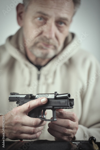 Man take care of semi automatic pistol handgun at home