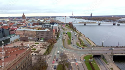 Aerial perspective of Riga, Latvia, highlighting the Daugava River, arched bridge, Riga TV Tower, Central Market pavilions, and urban architecture. photo