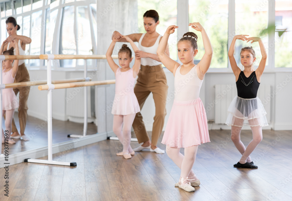 Obraz premium Little girls are learning various dance and ballet movements in the studio