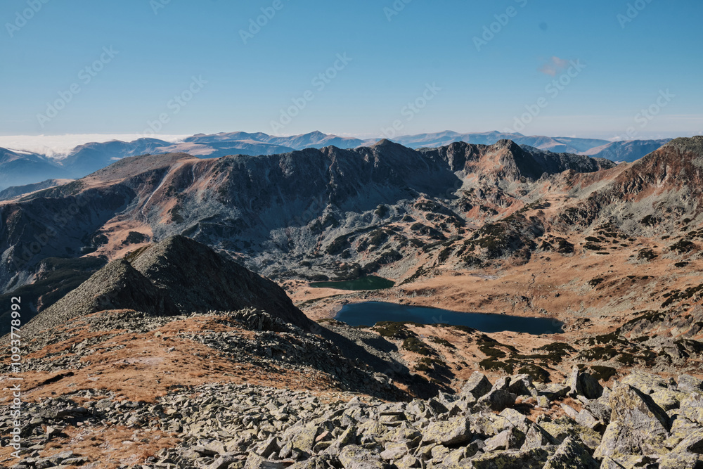 Stunning panoramic view of a mountain range with a crystal-clear lake nestled in the valley below. Rugged peaks and autumnal colors create a breathtaking landscape. Stunning panoramic view of a mountain range with a crystal-clear lake nestled in the valley below. Rugged peaks and autumnal colors create a breathtaking landscape.