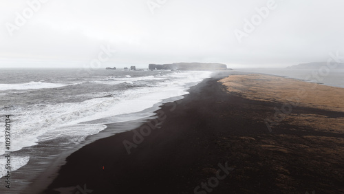 White waves crashing on reynisfjara black sand beach near vik i myrdal, iceland, creating a beautiful contrast