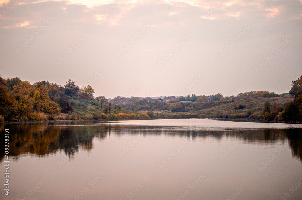 a calm lake, with reflections, against the backdrop of banks with reeds and a bright dawn sky a calm lake, with reflections, against the backdrop of banks with reeds and a bright dawn sky