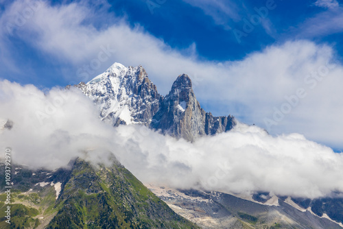 Petit Dru granite mountain wall and summit in Chamonix valley, french Alps. Prominent mountain peak in the Alps, stunning landscape view of the rocky peak covered with clouds, snow and ice