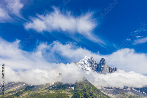 Petit Dru granite mountain wall and summit in Chamonix valley, french Alps. Prominent mountain peak in the Alps, stunning landscape view of the rocky peak covered with clouds, snow and ice
