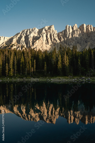 Mountains reflect in a serene lake, with trees in the foreground