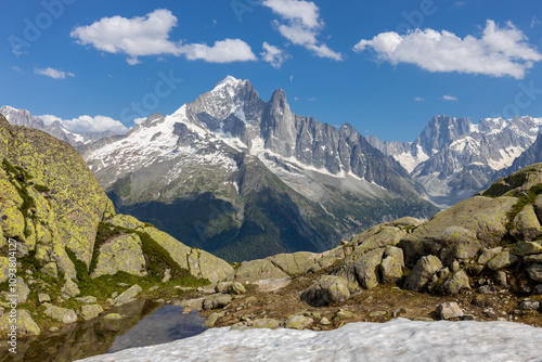 Petit Dru granite mountain wall and summit in Chamonix valley, french Alps. Prominent mountain peak in the Alps, stunning landscape view of the rocky peak covered with clouds, snow and ice
