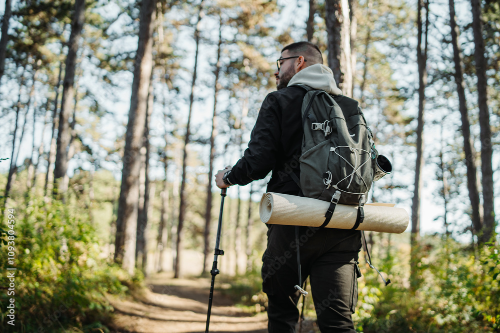 Young caucasian man hiking or trekking through the forest Young caucasian man hiking or trekking through the forest