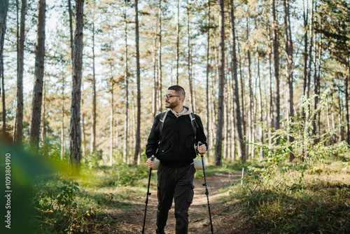 Young caucasian man hiking or trekking through the forest 