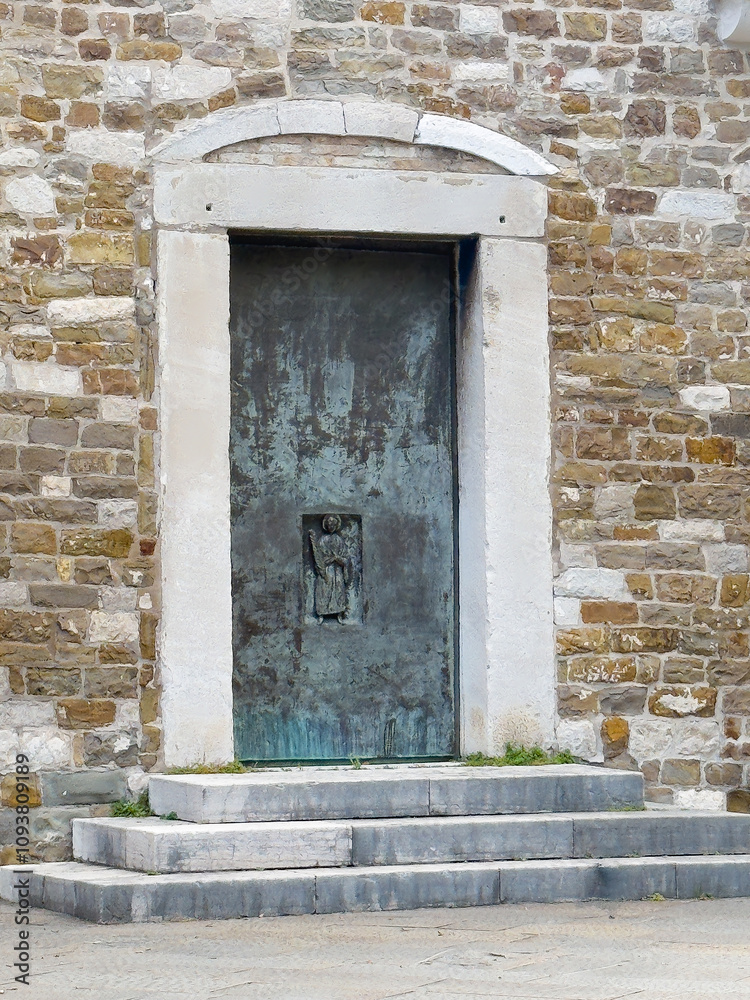 Trieste, Italy - June 27, 2024: Cattedrale di San Giusto Martire, Cathedral at San Giusto castle. Sculpture on closed metal door right side of main entrance Trieste, Italy - June 27, 2024: Cattedrale di San Giusto Martire, Cathedral at San Giusto castle. Sculpture on closed metal door right side of main entrance