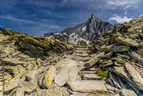 Petit Dru granite mountain wall and summit in Chamonix valley, french Alps. Prominent mountain peak in the Alps, stunning landscape view of the rocky peak covered with clouds, snow and ice