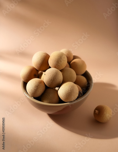 Fresh Longan fruit in a bowl on Pastel light brown background